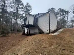 An early stage view of the backyard showing the groundwork for sod installation, with patches of bare soil and newly laid sod sections.