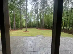 A sunny view of a newly completed 900+ square foot paver patio with Techo Bloc Champegne Grey pavers, featuring a sleek slate finish.