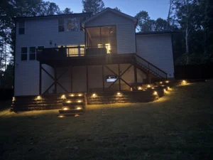 A captivating nighttime view of a house featuring a well-lit deck and patio area, with warm outdoor lights.