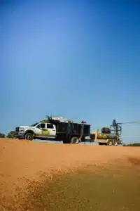 Hydroseeding truck spraying seed mixture across a large sloped site during erosion control project