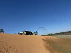 Professional hydroseeding equipment applying grass seed slurry to steep hillside for stabilization