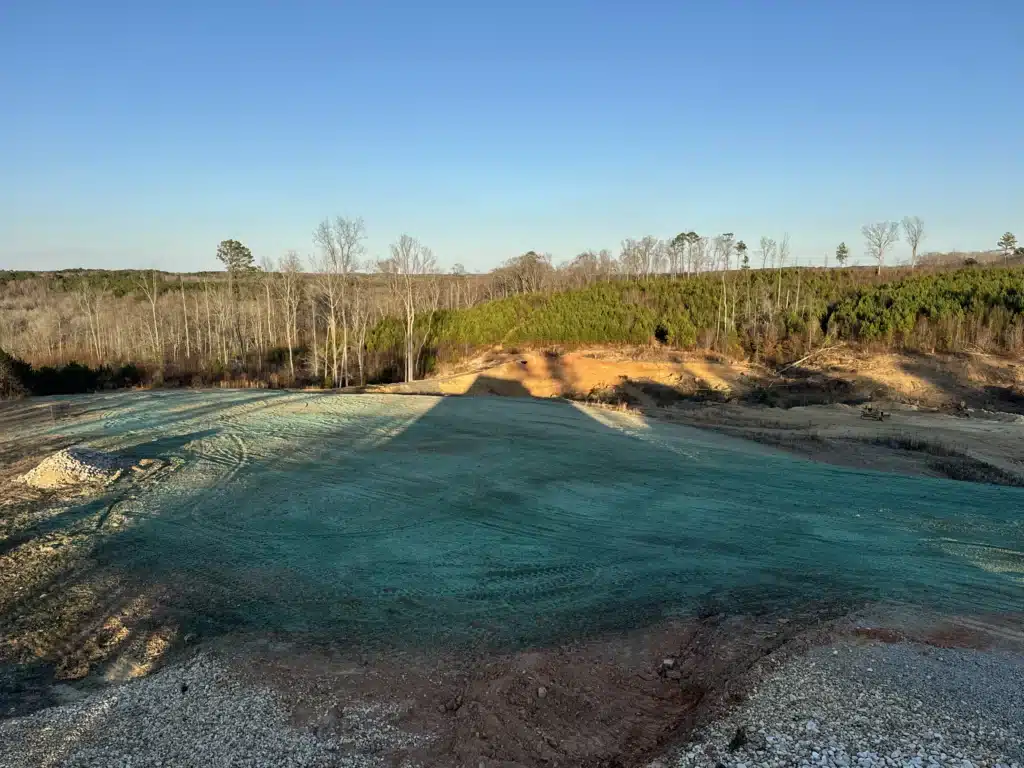 Hydroseeded 3-acre site in Zebulon, NC immediately after application showing freshly sprayed seed mixture covering slopes and drainage areas for erosion control