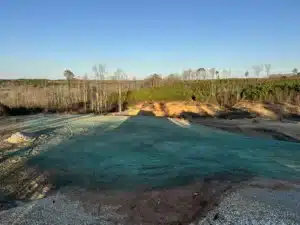 Hydroseeded 3-acre site in Zebulon, NC immediately after application showing freshly sprayed seed mixture covering slopes and drainage areas for erosion control
