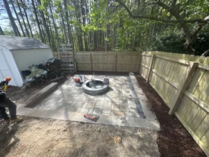 Custom paver patio installation in Durham NC with Techo-Bloc Champlain grey slate pavers, onyx black border, and Weston stone fire pit
