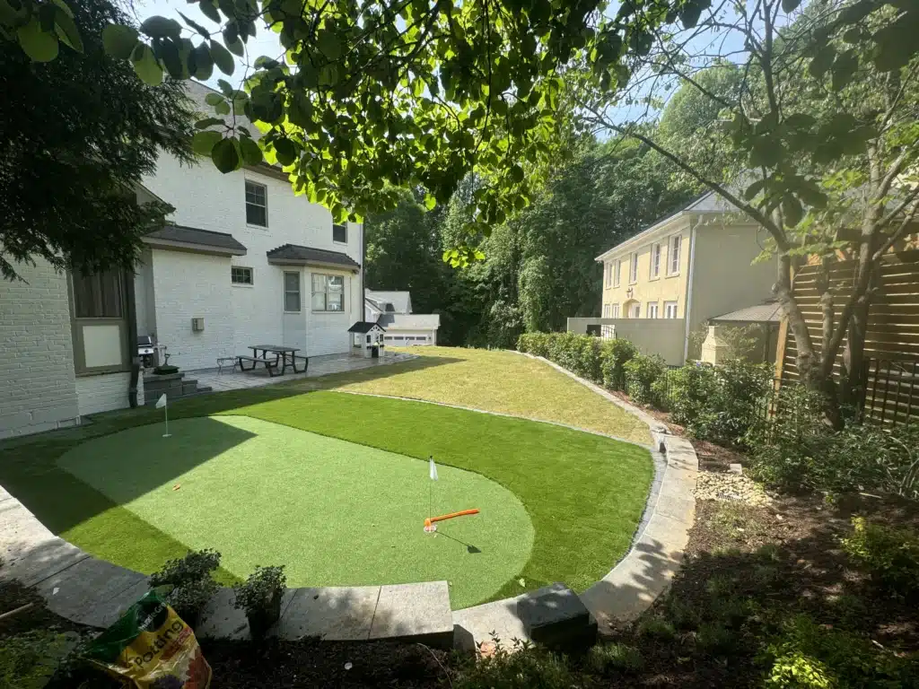 Artificial turf backyard with custom putting green, clean edging, and low-maintenance landscaping in Raleigh, NC