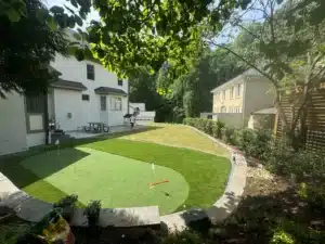 Artificial turf backyard with custom putting green, clean edging, and low-maintenance landscaping in Raleigh, NC