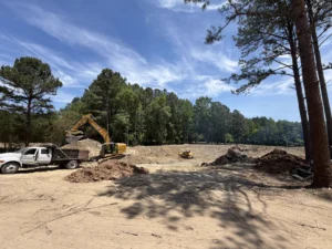 Excavator and bulldozer excavating a custom half-acre pond after land clearing and grading on a residential property in Creedmoor, NC.