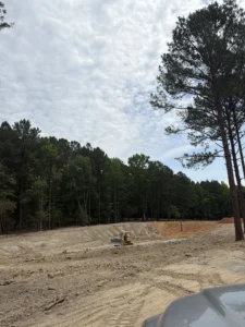Bulldozer performing final grading and shaping inside a newly excavated half-acre pond during construction in Creedmoor, NC.