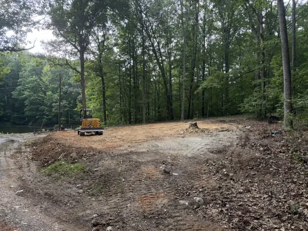 Cleared and graded residential lot in Asheboro, NC after house demolition and tree removal, opening up views of the pond and preparing the property for new home construction.