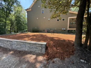 Stone retaining wall stabilizing a sloped residential yard as part of an erosion control project in Apex, NC
